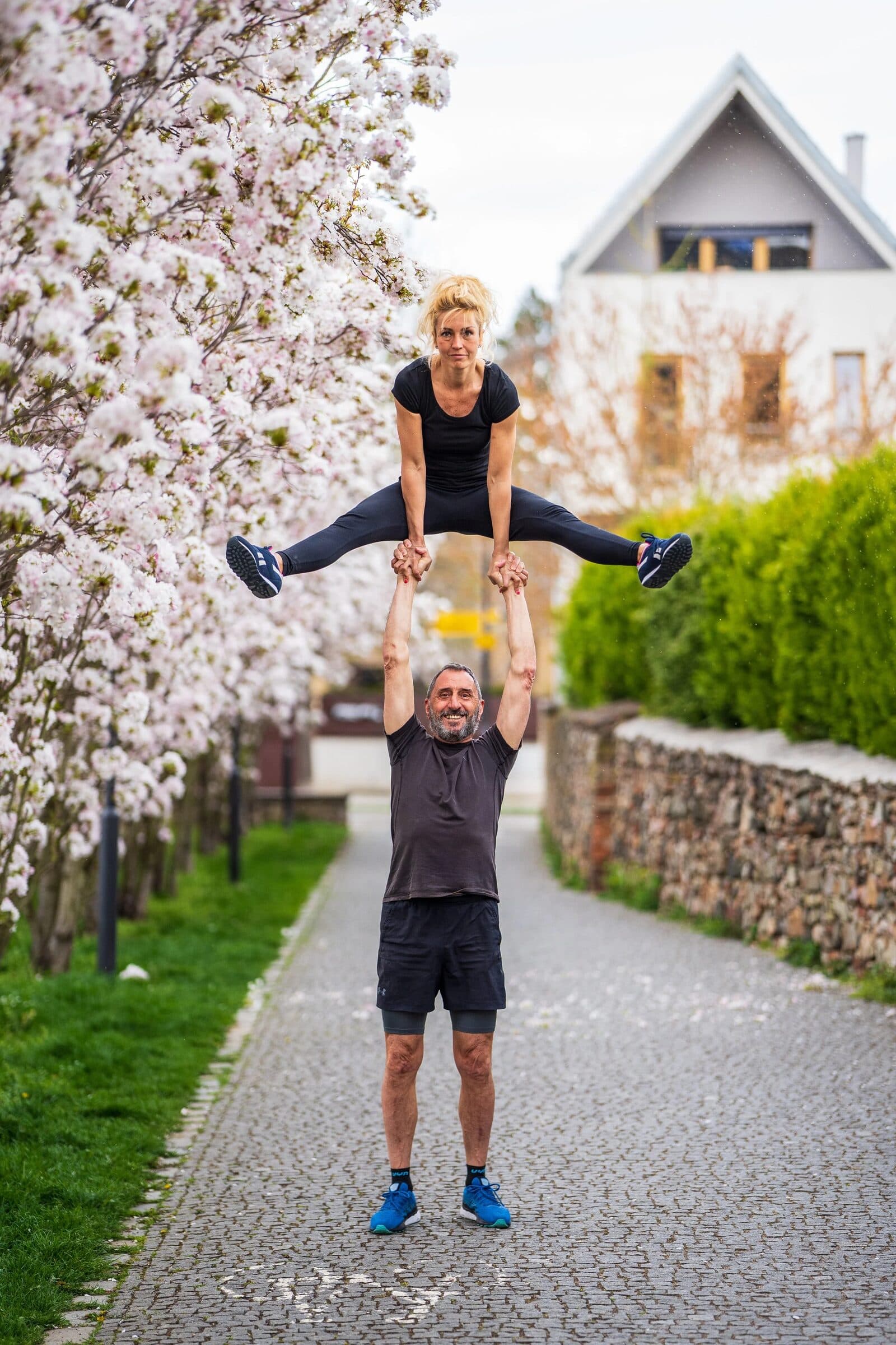 A flyer in a high straddle above her base under a blossoming tree